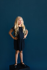 cute girl with long blond hair in a dark  dress. studio shot on dark background