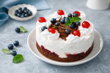 Chocolate cake, white cheesecake decorated with blueberries, cherry, brown chocolate and whipped...