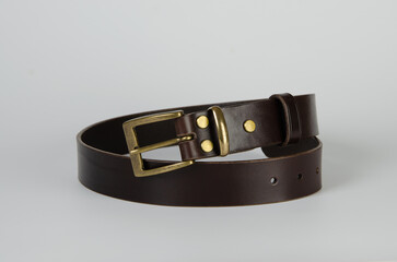 brown Italian leather belt with brass buckle and brass screws on a light background