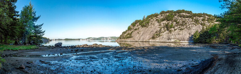 Fototapeta na wymiar Panorama of a small rocky beach of Gandsfjord fjord near Dale with a tourist setting a campfire, Sandnes, Norway, May 2018