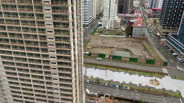 Raise building load to height. Crane lowers loads at construction site. Work process. Crane lifts materials on roof for construction decoration. raised telescopic boom on site. sling hoist crane arm