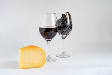 Smoked Gouda cheese, glass of wine, on white background with copy space.