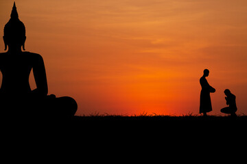 Silhouette with black buddha and people worshiping monks on sunset background.