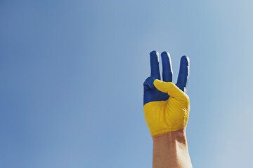 Man's hand lit by sunshine painted in colors of Ukrainian national flag showing a traditional...