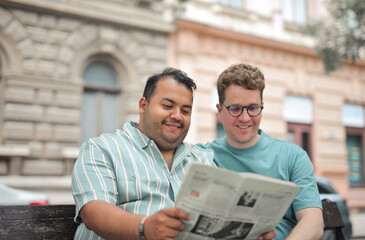 portrait of young homosexual couple reading newspaper
