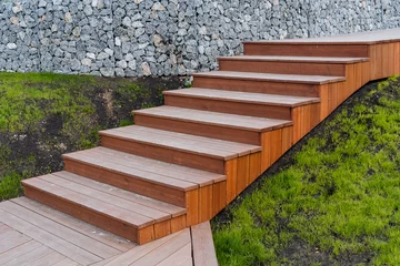 Fototapete Rund Wooden staircase assembled from boards, landscape design in a private house, brown staircase, descent up the steps, green grass lawn. © Aleksey