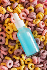 serum in a mock-up dropper glass bottle on the background of multi-colored breakfast cereals, creative advertising