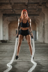 Fitness woman working out with heavy ropes. Athletic girl