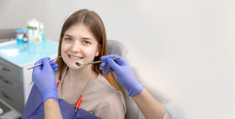 Smiling pretty woman is having her teeth examined by dentist in clinic. Concept of caries treatment