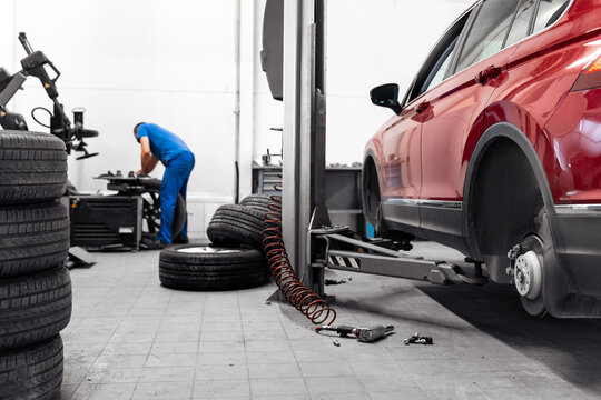 Repairman balances wheel and installs tubeless tire of car on balancer in workshop