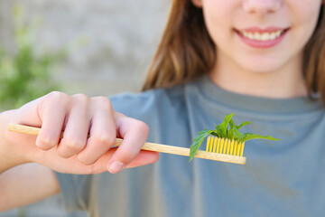The girl holds a toothbrush with mint in her hand. Selective focus on the mint toothbrush.