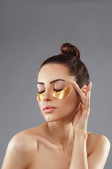 Beauty woman applying golden anti-aging under-eye mask