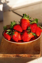 Fresh strawberries in a bowl on wooden table.