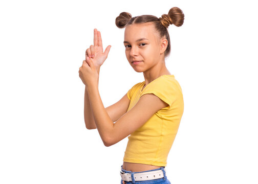 Portrait of funny teen girl doing gun gesture getting ready to shoot. Caucasian young teenager showing raised gun gesture, isolated on white background. Child holding symbolic gun. Emotions and signs.