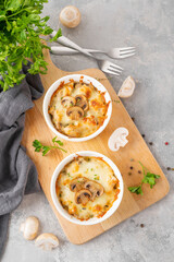 Baked julienne with mushrooms and chicken in a creamy sauce with cheese on top on a gray concrete background. Selective focus. Copy space.