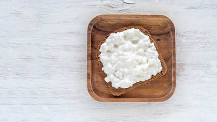 Sandwich with cottage cheese on wooden background.