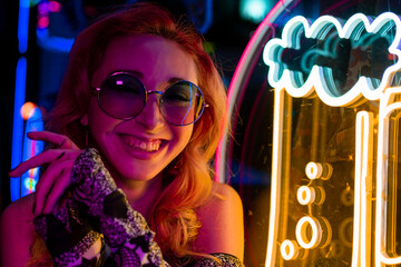 Happy woman standing and smiling on neon studio background. Beautiful female half-length portrait....