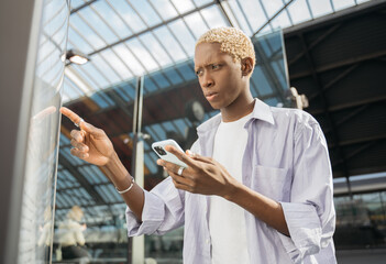 Portrait of pensive African American tourist using digital travel map, searching best way, touching...