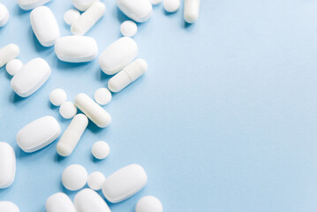 
White pills on a pastel blue background. Capsules and round pills close-up. health care and medicine.