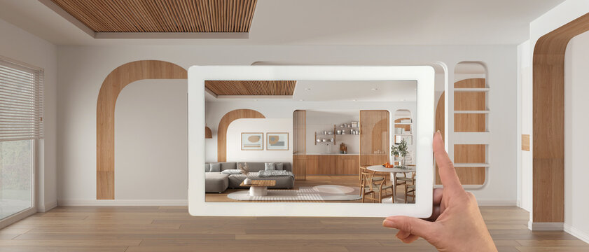 Augmented reality concept. Hand holding tablet with AR application used to simulate furniture and design products in panoramic empty interior, living room, dining room and kitchen