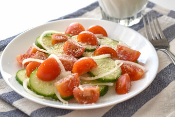 Cucumber and cherry tomatoes salad on a white plate.  