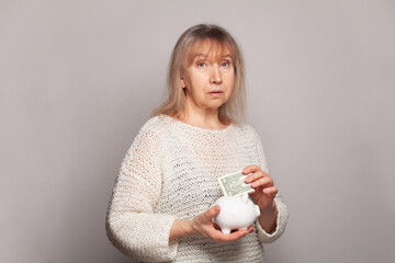 Sed senior woman with a piggy bank and us dollar money.