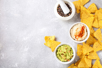 Hummus and guacamole with nachos on a gray background. Selective focus. Copy space