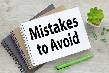 MISTAKES TO AVOID several notebooks on the table. text on the page of the notebook. potted plant and green handle