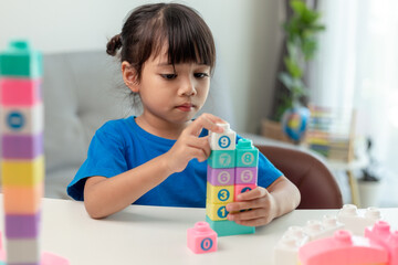 Adorable little girl playing toy blocks in a bright room