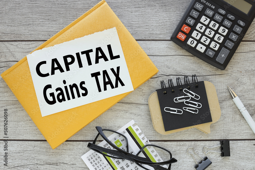 Poster capital gains tax cgt. torn page from a notebook with text. yellow notepad on a wooden background. n