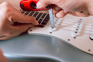 Guitar master changing or making electric guitar pickup height measurements