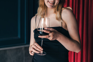 Close-up, a glass of wine in the hands of a woman in an evening dress.