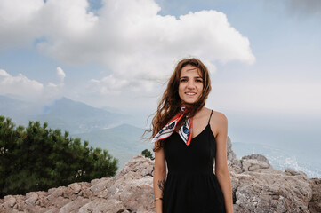 Naklejka premium A young fearless woman poses after crossing a rope bridge over a precipice high in the mountains.