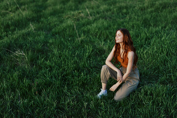 Fototapeta premium Young sportswoman warming up on the grass in the park on a sunny evening