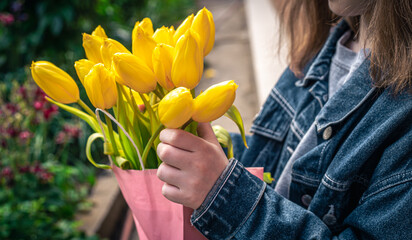 Close-up, a bouquet of yellow tulips in the hands of a little girl.