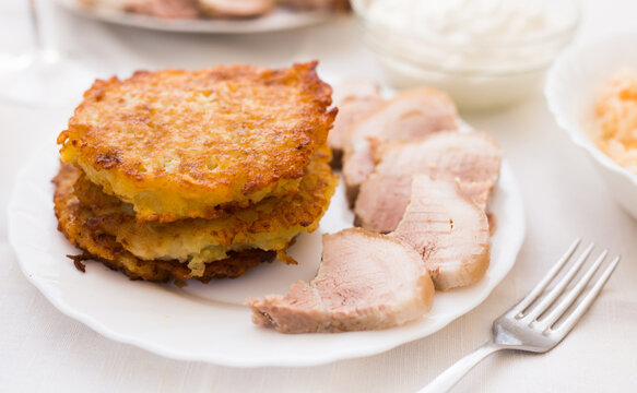 Fried grated potato pancakes with meat on white plate