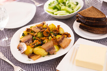 baked potatoes with chanterelles and bacon served with herbs on white plate