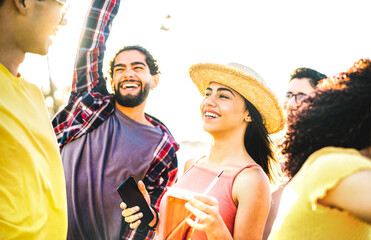 Happy guys and girls dancing at sunset on vacation days - Summer life style concept with friends having fun together at spring break beach festival - Bright vivid contrast filter with sunshine halo