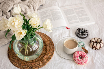 Cozy composition with a bouquet of tulips in a glass vase and a cup of coffee.