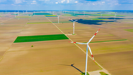 Aerial view of several windmills, wind generators, turbines, producing renewable clean energy by converting kinetic energy