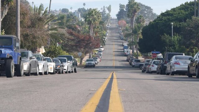 American residential district, suburban street. Cars and palm trees in city near Los Angeles. Ocean Beach neighborhood in San Diego, California USA. Road marking, yellow dividing line, low angle view.