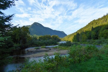 Jacques-Cartier National Park in province of Quebec, Canada, with green foliages, crystal clear water, cloudy sky and mountains at the water’s edge of the Jacques-Cartier River