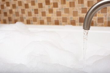 A view of a faucet pouring water into a hot tub during a bubble bath session.