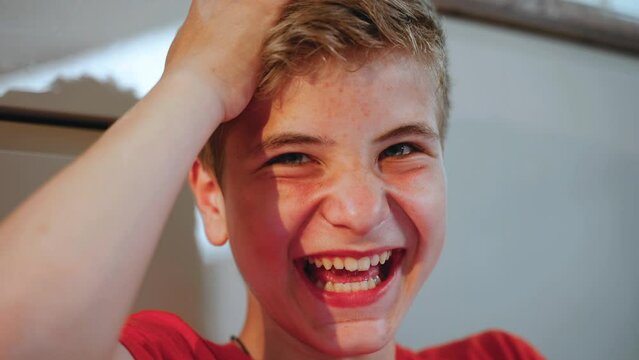 Face of teenage boy close up. The guy sees something on phone and is surprised and happy and laughs and happily fools. Problem skin. Black spots and pimples on skin. Acne. Emotion of unspeakable joy