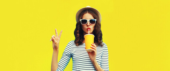 Portrait of stylish young woman drinking fresh juice wearing summer straw hat, sunglasses and...