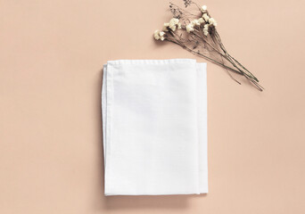 Stack of fabrics over beige background. Flat lay with white folded cloth for mockup.