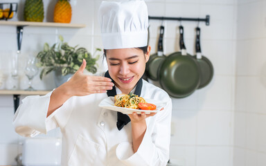 Portrait beautiful Asian professional female chef wearing white uniform, hat, holding plate of...