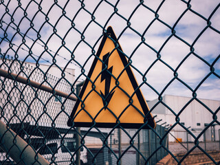 high voltage warning sign on a high-voltage substations mesh fence