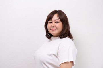 Obraz premium Young beautiful Asian oversize women smile with positive emotion, feeling happy and proud with her body size. Portrait shot on white background with copy space.
