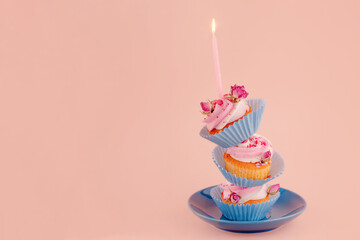 three birthday berry muffins  on top of each other in blue wrappers with a candle on top on a...